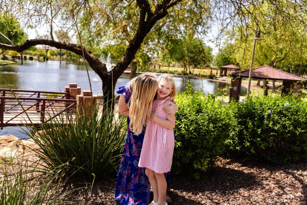 Mother hugging her smiling daughter beside the lake at Anthem Community Park
