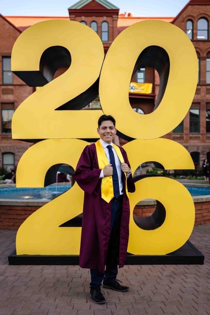 ASU graduate posing by the 2026 sign at Tempe campus