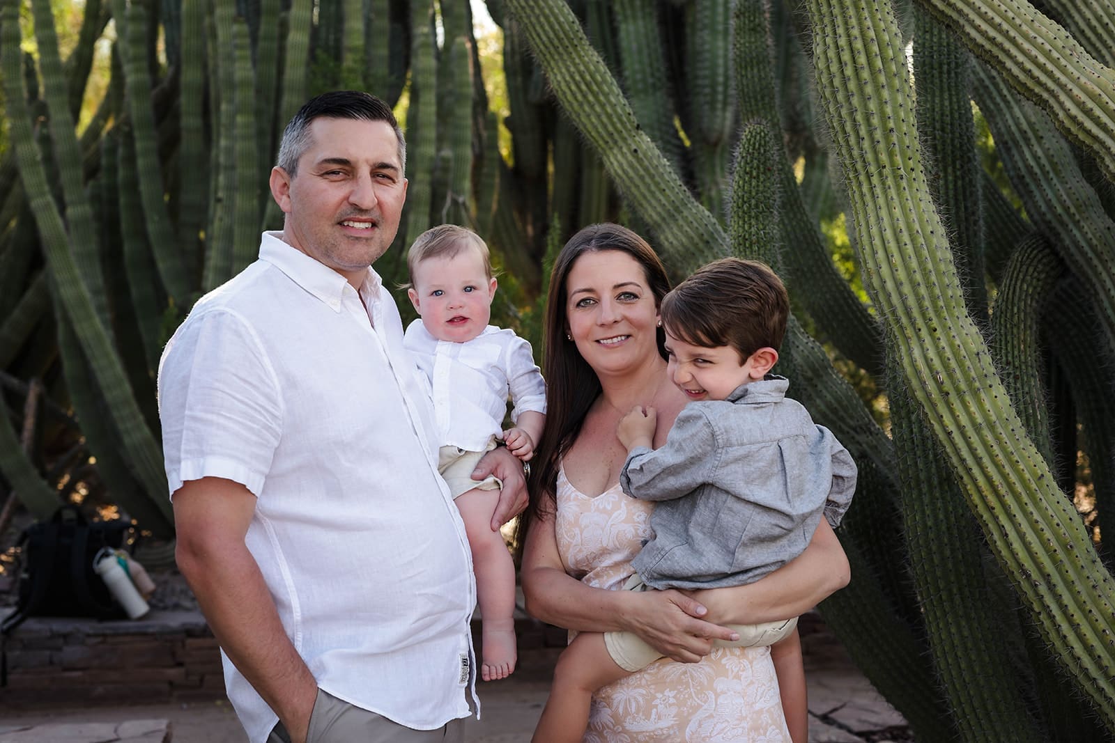 Family of four posing together among cactus at Desert Botanical Garden in Phoenix.