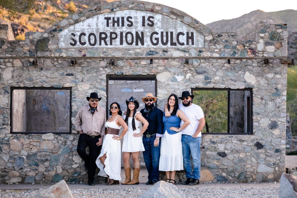 Family standing in front of the historic Scorpion Gulch stone sign during a photo session at South Mountain in Phoenix, Arizona.