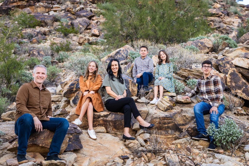 Family sitting together on desert rocks during a photo session at White Tank Mountain Regional Park near Phoenix, Arizona.