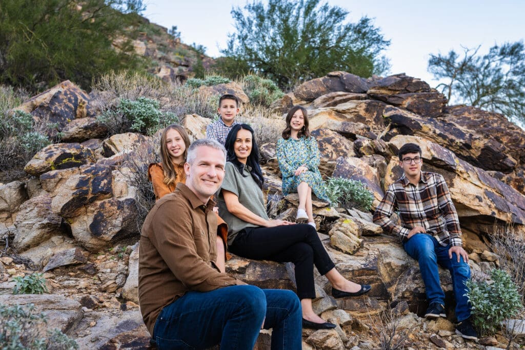 Family sitting together on desert rocks during a photo session at White Tank Mountain Regional Park near Phoenix, Arizona.